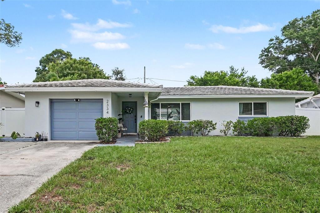 A single-story house with a gray garage, light-colored exterior, and a front lawn — 2334 TUDOR LANE, CLEARWATER, FL