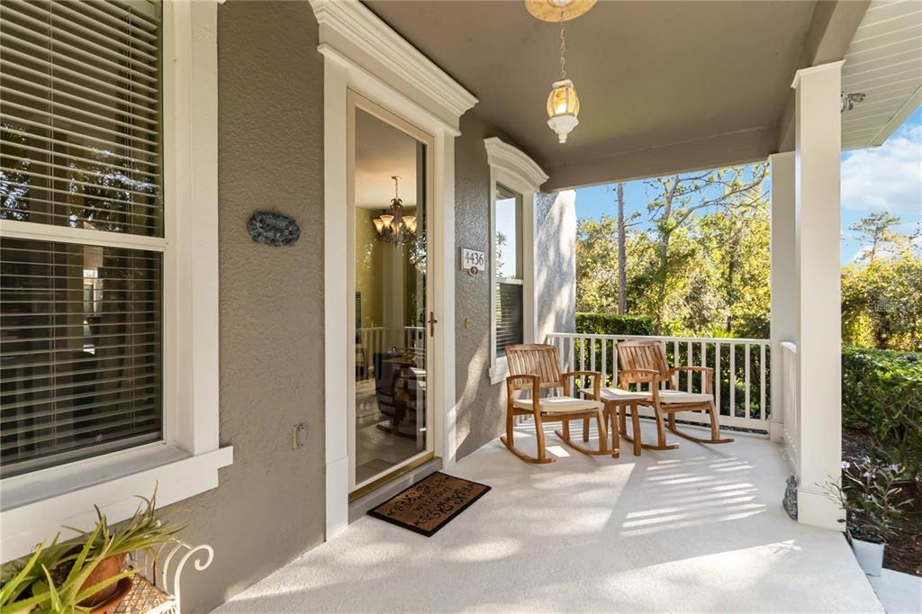 A covered front porch features two wooden rocking chairs, a door, and a light fixture — 4436 CLEARY WAY, ORLANDO, FL
