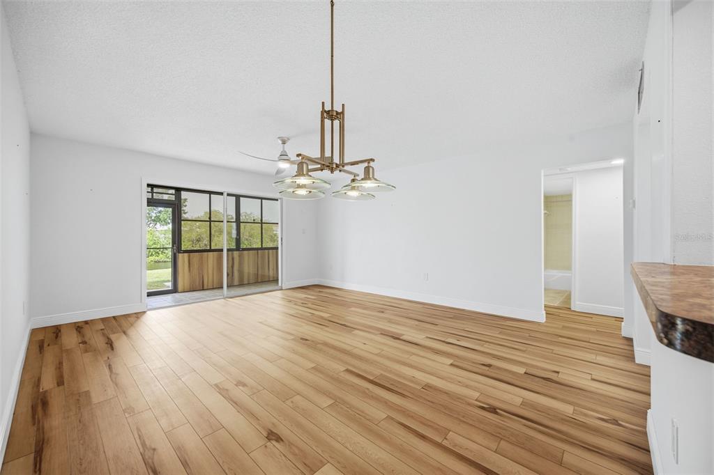 A dining area with wood-look flooring, a modern chandelier, and a sliding glass door — 4555 MARINE PARKWAY UNIT 106, NEW PORT RICHEY, FL
