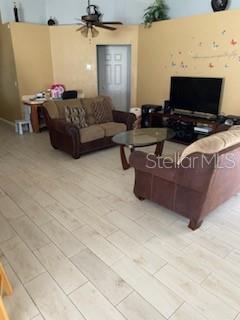 A living room features light tile flooring, two brown sofas, a coffee table, and television — 1146 BLUEGRASS DRIVE, GROVELAND, FL
