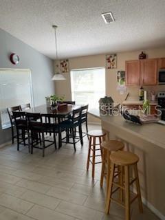 A dining area with a dark wood table and chairs next to a kitchen counter — 1146 BLUEGRASS DRIVE, GROVELAND, FL