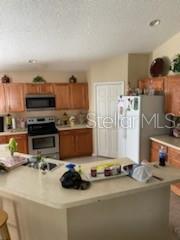 A kitchen features wood cabinets, stainless steel appliances, and a large central island — 1146 BLUEGRASS DRIVE, GROVELAND, FL