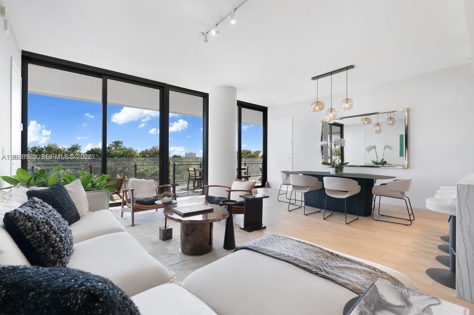 A modern living and dining area features floor-to-ceiling windows, light wood floors, and neutral furniture — 8701 Collins Ave # 404, Miami Beach FL 33154, MIAMI BEACH, FL