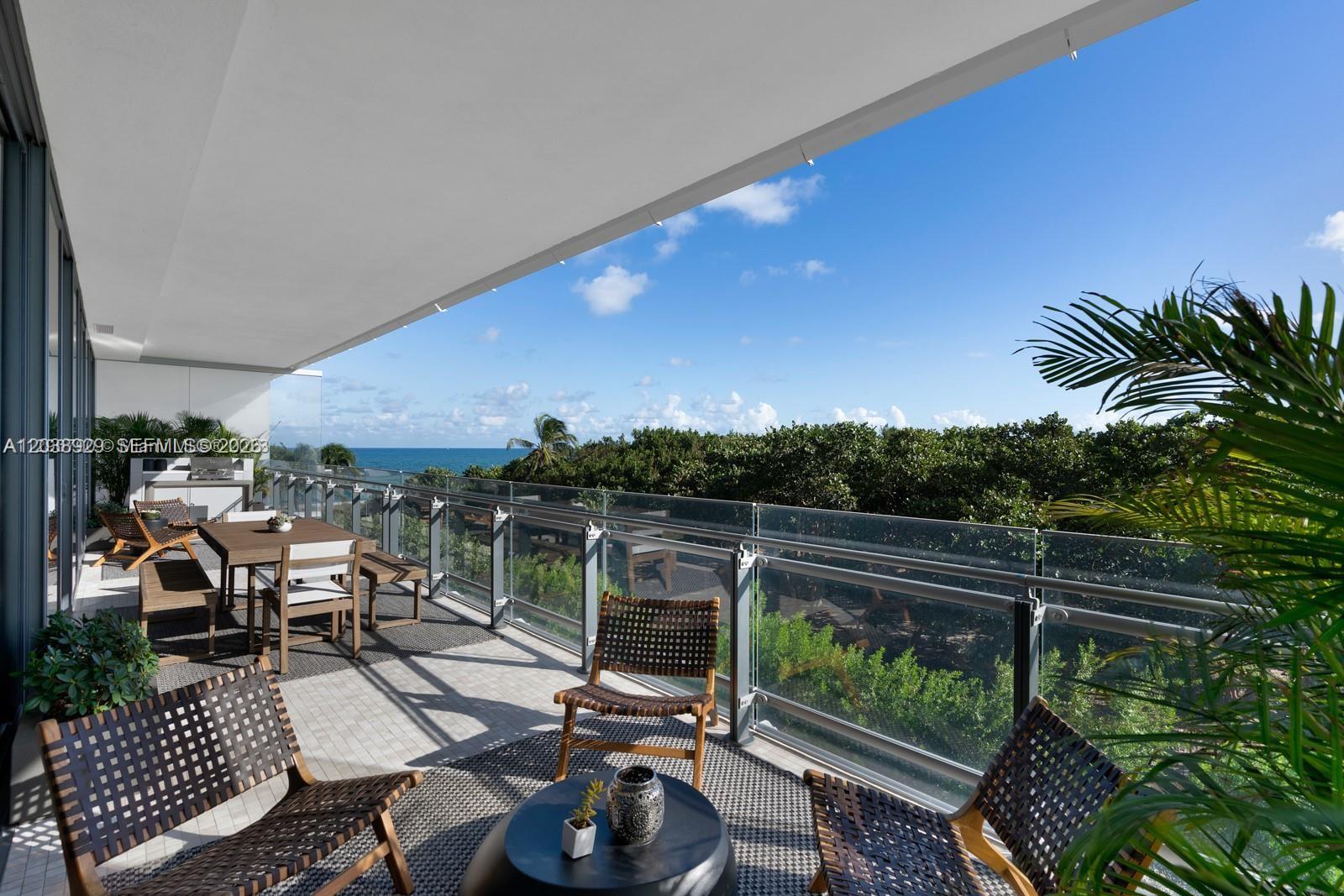 A spacious balcony features outdoor furniture, a glass railing, and views of the ocean — 8701 Collins Ave # 404, Miami Beach FL 33154, MIAMI BEACH, FL