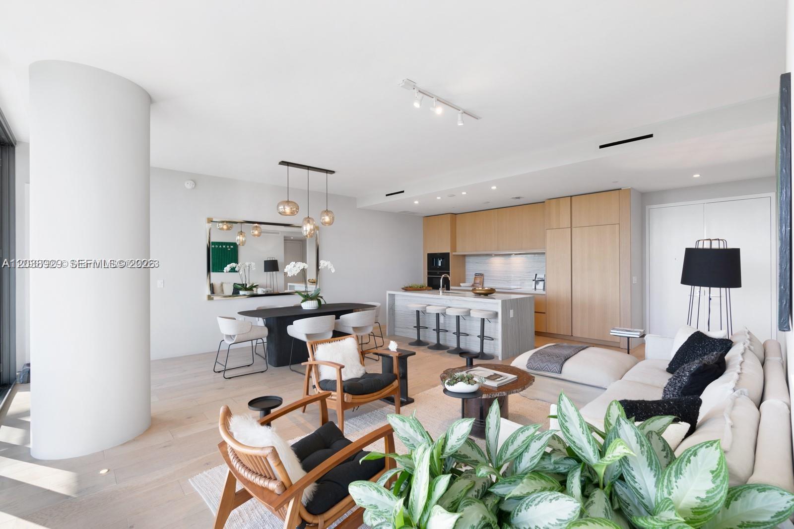An open-concept living and dining area features light wood floors, modern furniture, and a kitchen — 8701 Collins Ave # 404, Miami Beach FL 33154, MIAMI BEACH, FL
