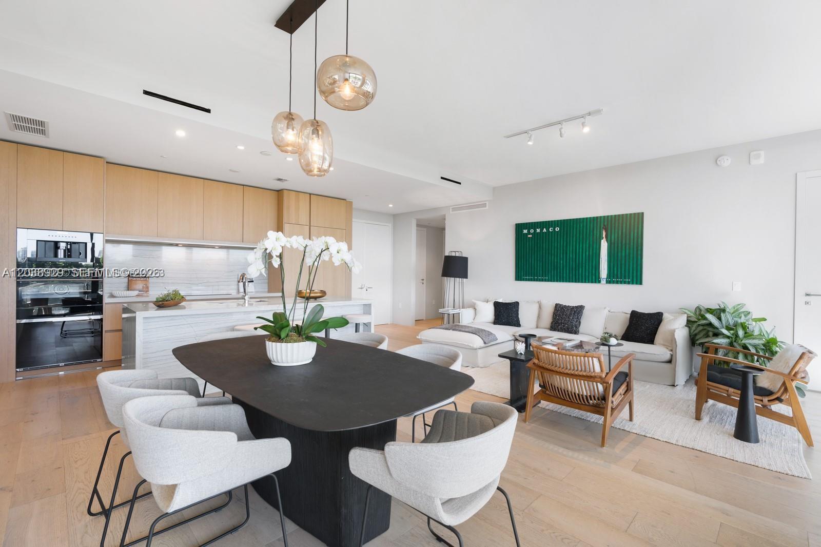 An open-concept living and dining area features light wood floors, modern cabinetry, and neutral furniture — 8701 Collins Ave # 404, Miami Beach FL 33154, MIAMI BEACH, FL