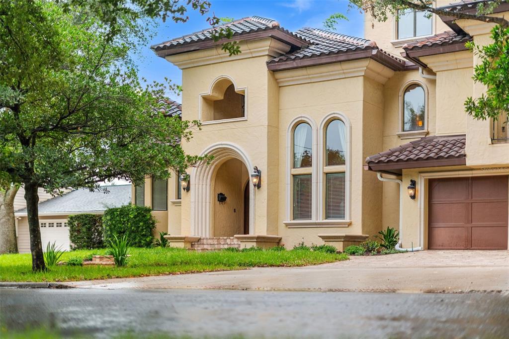 A two-story stucco house with a tiled roof, arched entryway, and an attached garage — 1830 GERDA TERRACE, ORLANDO, FL