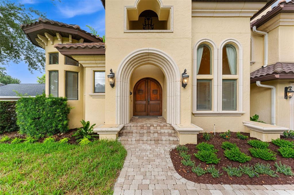 The exterior of a beige stucco house features an arched wooden double door entryway — 1830 GERDA TERRACE, ORLANDO, FL