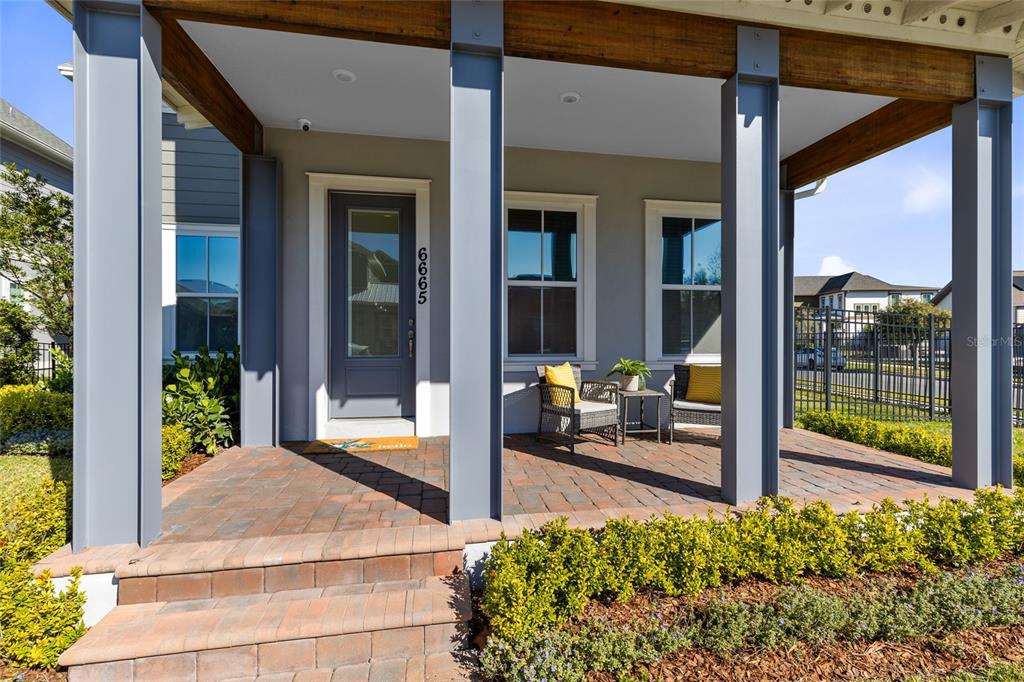 A covered front porch features brick pavers, grey support columns, and a glass-paneled front door — 6665 BRIDGMAN STREET, ORLANDO, FL