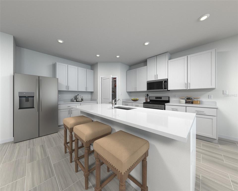 A modern kitchen features white cabinets, stainless steel appliances, a large island, and tile flooring — 100 OUTBACK HIDEAWAY AVENUE, NOKOMIS, FL