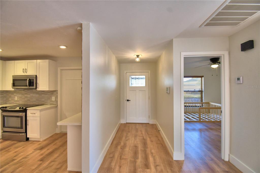 A view of a hallway with wood-look flooring leading to a white front door — 23 BUCK CIRCLE, HAINES CITY, FL
