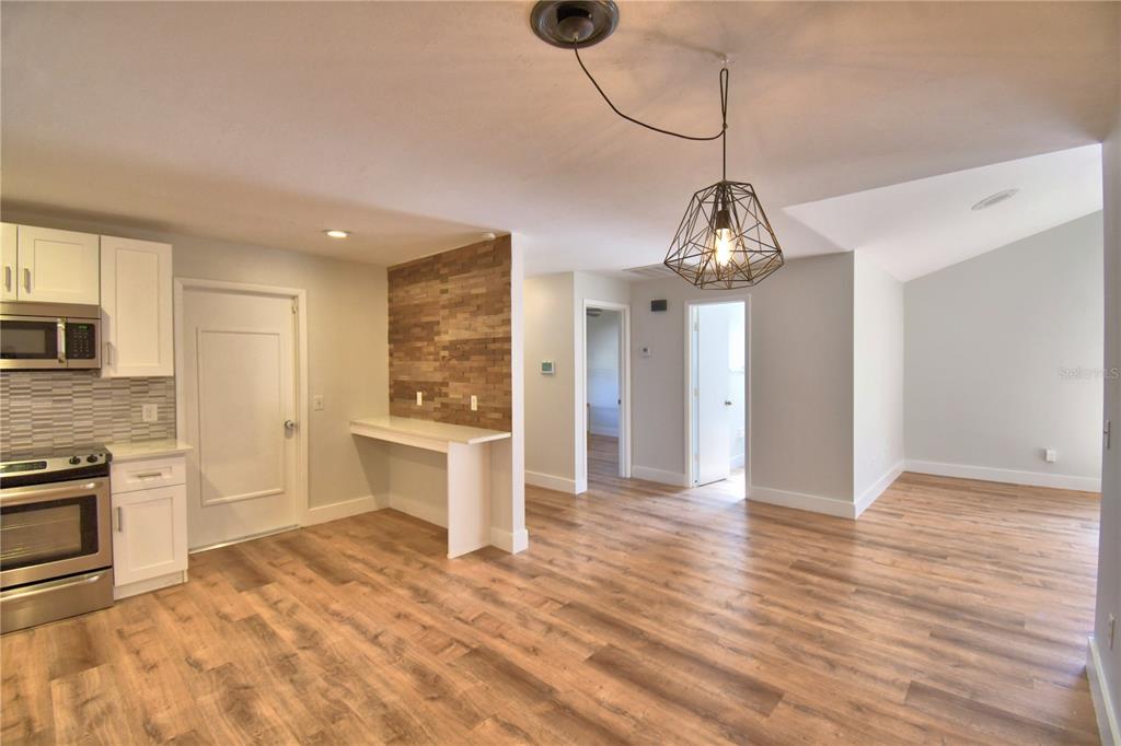 A kitchen and dining area with wood-look flooring, white cabinets, and a wood-accented wall — 23 BUCK CIRCLE, HAINES CITY, FL