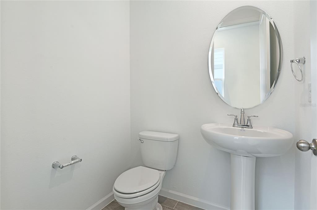 A small bathroom features a pedestal sink, an oval mirror, and a white toilet — 1253 DAISY HILL AVENUE, DUNDEE, FL