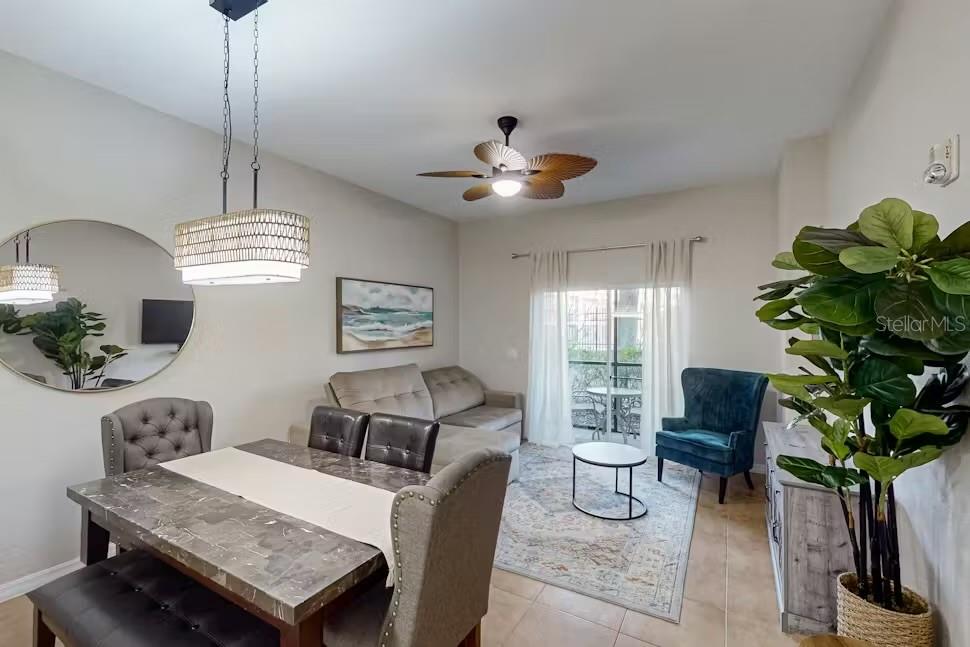 A dining and living area features a stone-topped table, gray sofa, and a ceiling fan — 903 GRAN BAHAMA BOULEVARD UNIT 903, DAVENPORT, FL
