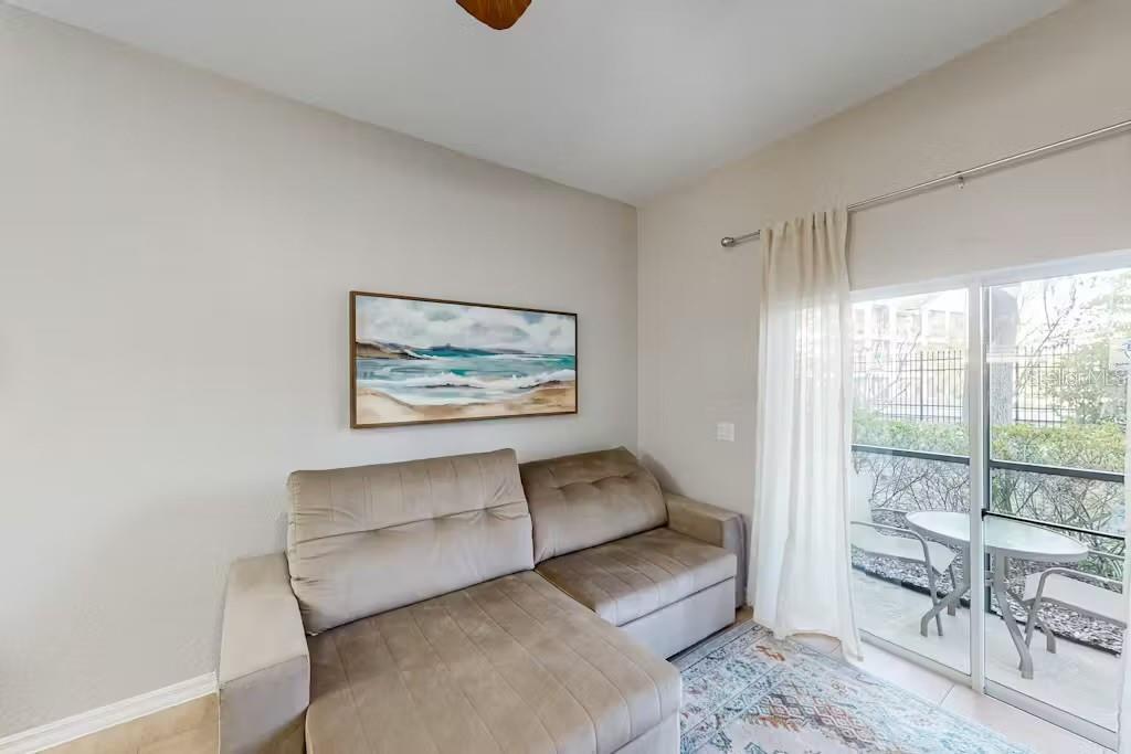 A living room features a tan sectional sofa, a coastal wall print, and sliding glass doors — 903 GRAN BAHAMA BOULEVARD UNIT 903, DAVENPORT, FL