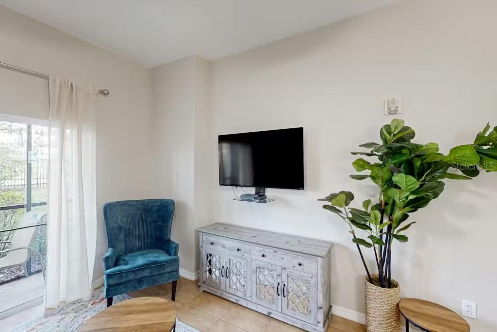 A living room features a wall-mounted television, a light wood console, and a blue chair — 903 GRAN BAHAMA BOULEVARD UNIT 903, DAVENPORT, FL