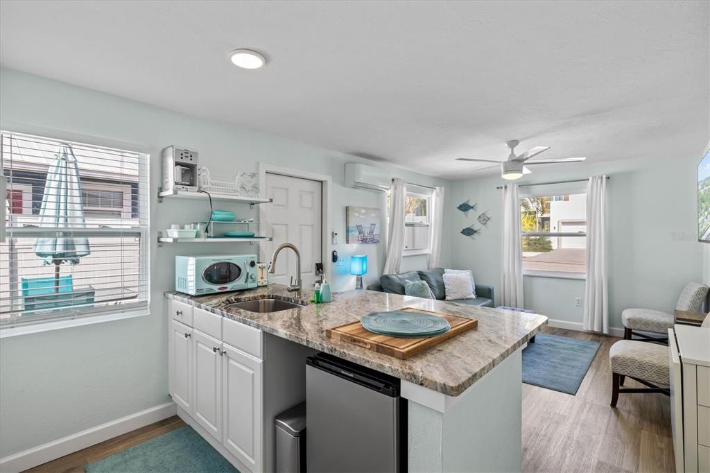 A small kitchen with a granite island and a living area with a ceiling fan — 2084 GROVE STREET UNIT B, SARASOTA, FL