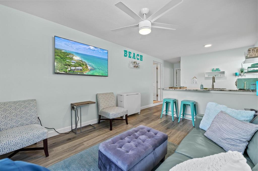 A living room with a television, a purple ottoman, and a kitchen breakfast bar — 2084 GROVE STREET UNIT B, SARASOTA, FL