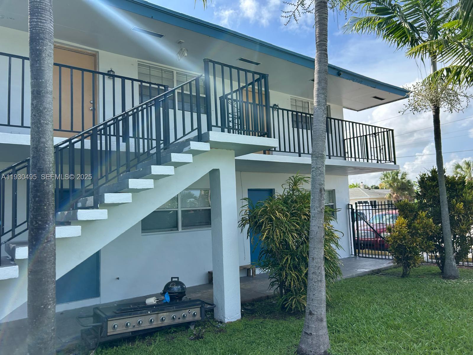 An exterior view of a two-story apartment building featuring an outdoor staircase and balcony — 201 W Blue Heron Blvd, Riviera Beach FL 33404, RIVIERA BEACH, FL