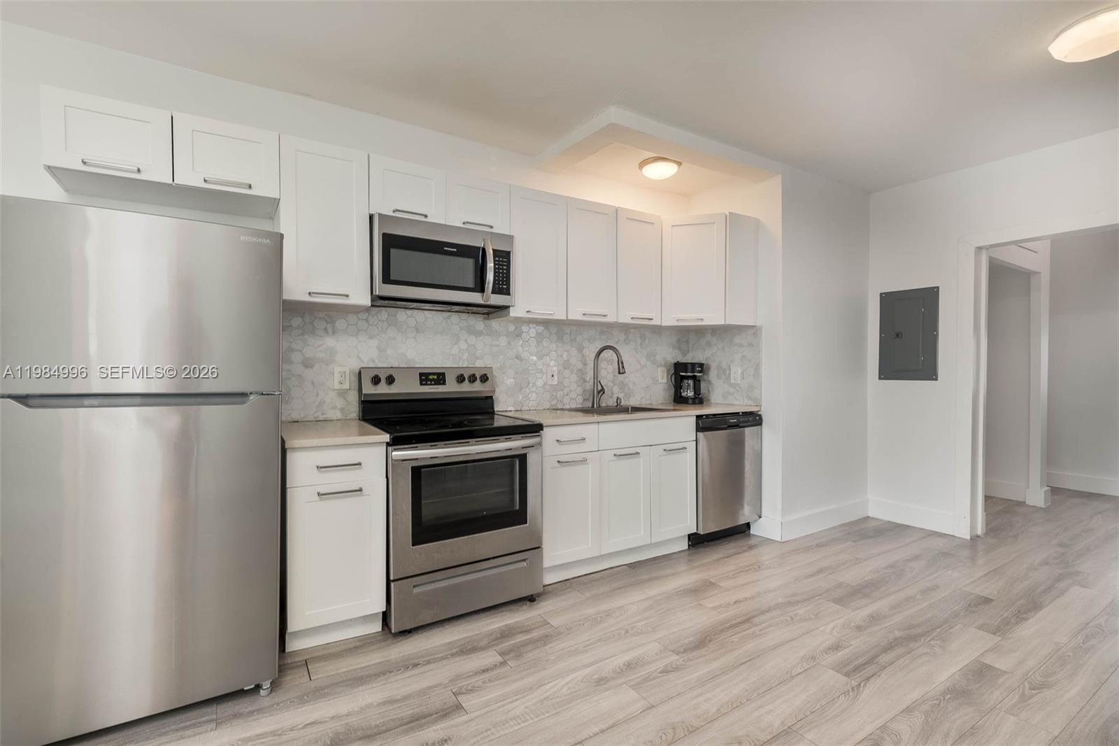 A kitchen features white cabinets, stainless steel appliances, and light wood-look flooring — 1275 Marseille Dr # 35, Miami Beach FL 33141, MIAMI BEACH, FL