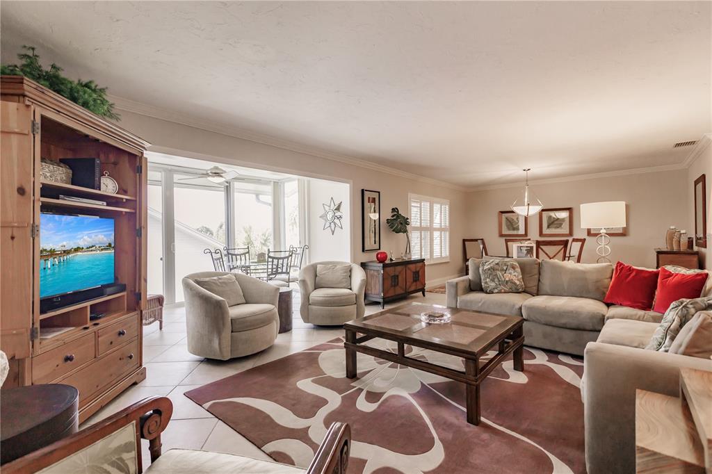 A living room with tile floors, a large area rug, and a view of a patio — 6052 W PEPPERTREE WAY UNIT 235B, SARASOTA, FL