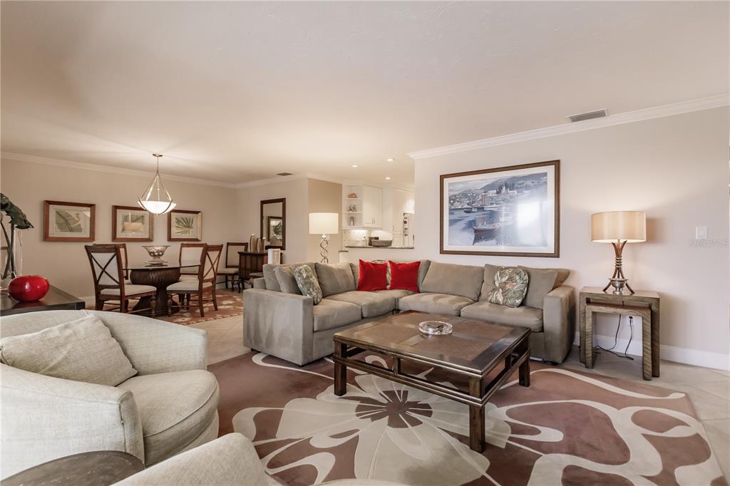 A living room with a sectional sofa, coffee table, and adjacent dining area — 6052 W PEPPERTREE WAY UNIT 235B, SARASOTA, FL