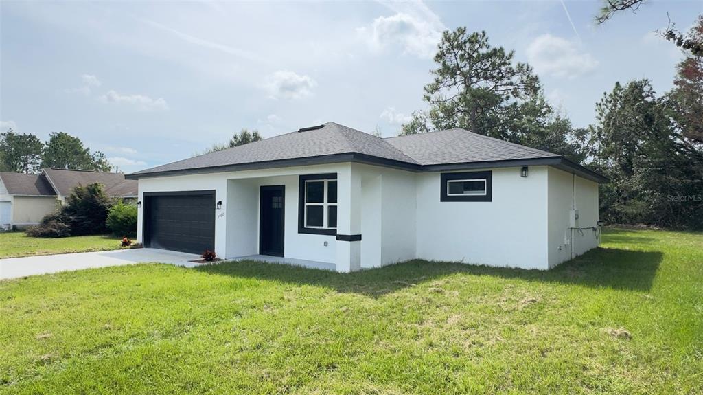 A single-story house with white stucco walls, a dark garage door, and a dark roof — 3462 W CENTURY BOULEVARD, CITRUS SPRINGS, FL