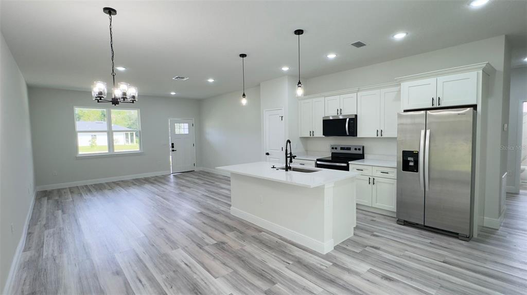 A kitchen and living area feature white cabinets, a central island, and light wood flooring — 3462 W CENTURY BOULEVARD, CITRUS SPRINGS, FL