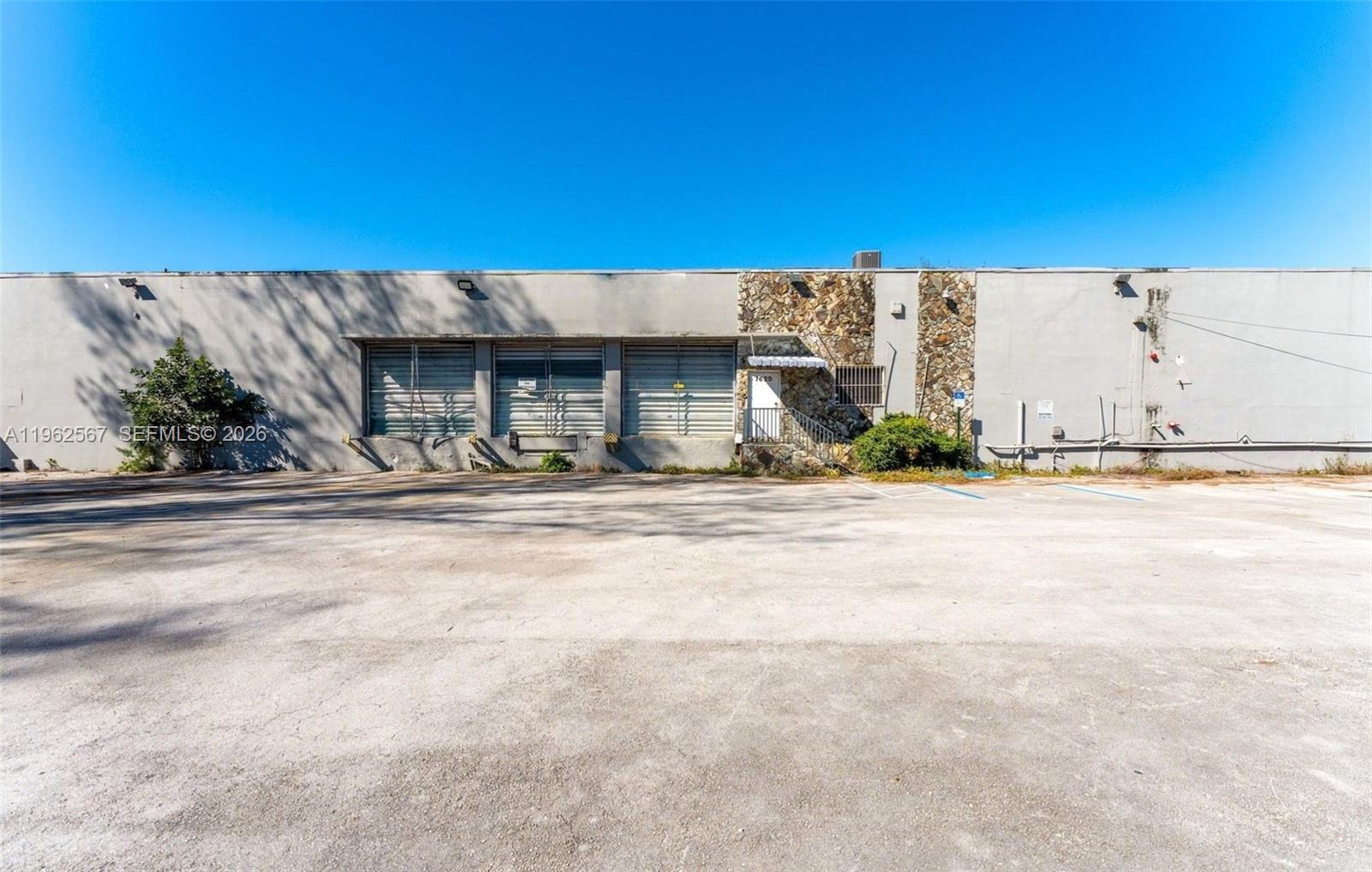 A single-story industrial building with three loading bays and a stone-accented entrance — 7620 W 2nd Ct, Hialeah FL 33014, HIALEAH, FL