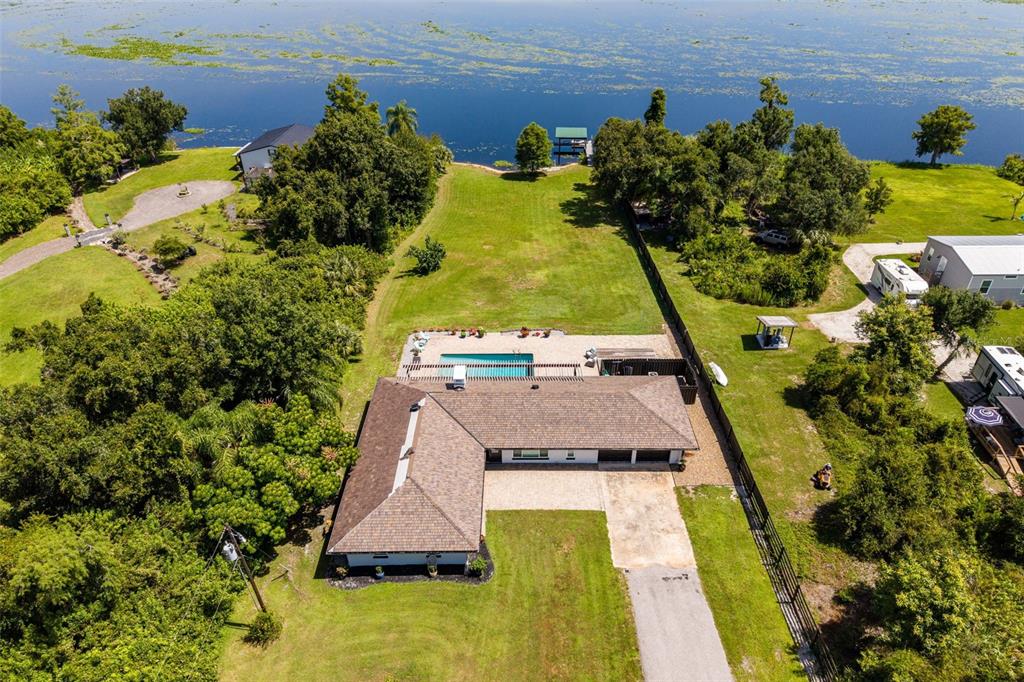 An aerial view shows a house with a pool, large yard, and lakefront access — 37951 WASHINGTON LOOP ROAD, PUNTA GORDA, FL