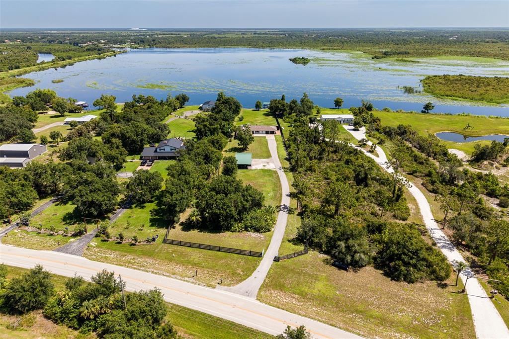 An aerial view shows several houses on a large, grassy lot bordering a lake — 37951 WASHINGTON LOOP ROAD, PUNTA GORDA, FL