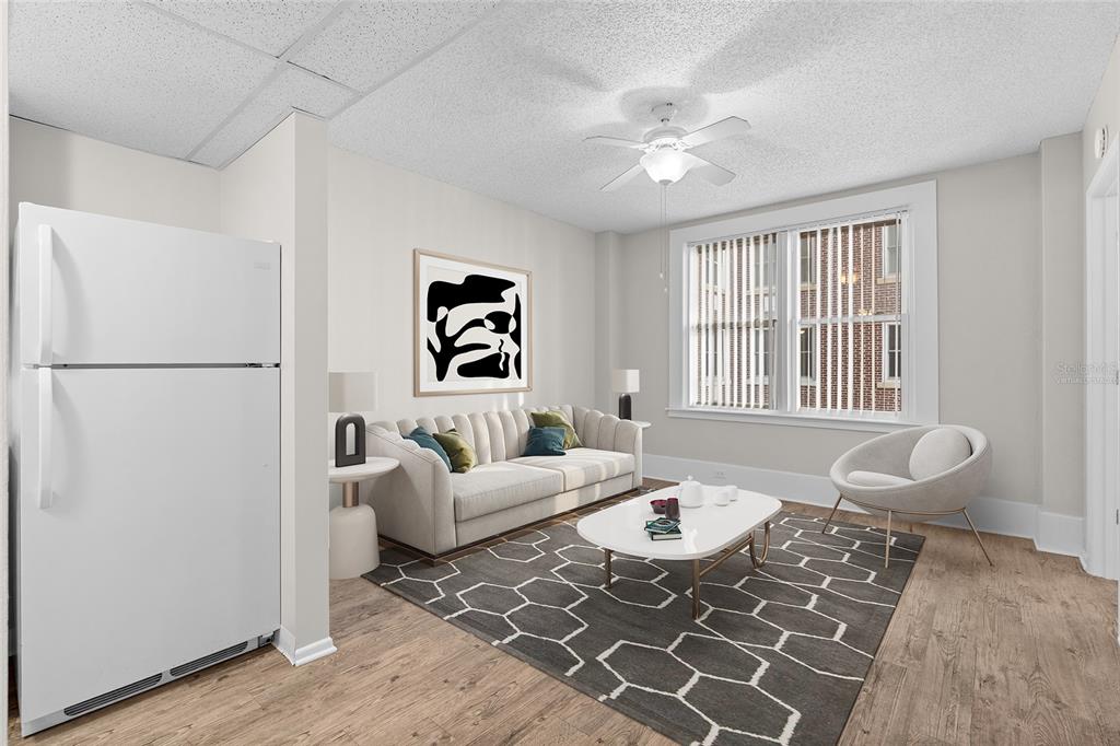 A virtual staging of a living room with a sofa, coffee table, and white refrigerator — 411 1ST AVENUE N UNIT 502, ST PETERSBURG, FL