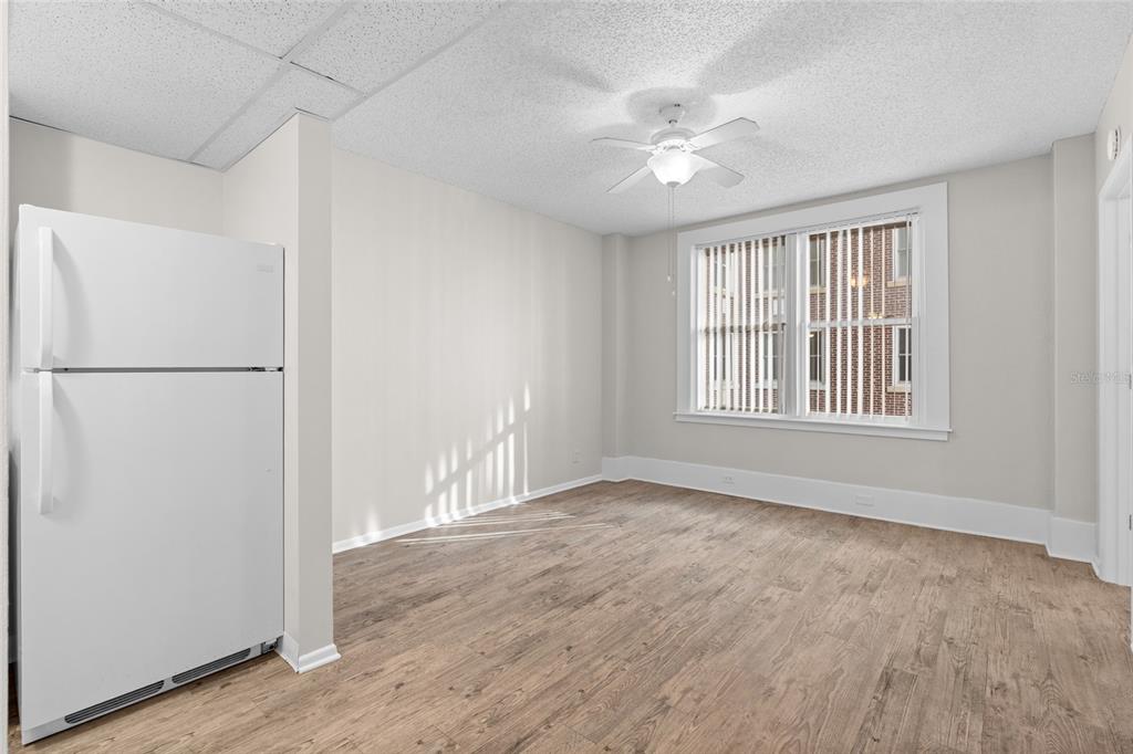 A room with wood-look flooring, a white refrigerator, a ceiling fan, and a large window — 411 1ST AVENUE N UNIT 502, ST PETERSBURG, FL