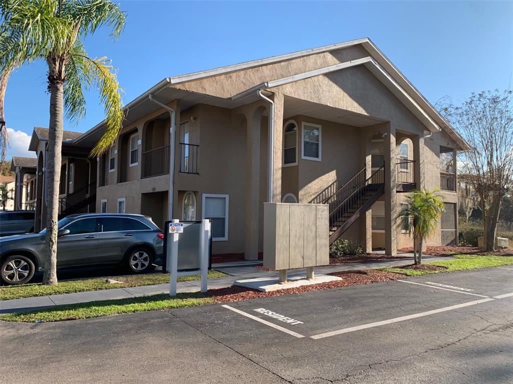 A two-story apartment building exterior with a parking lot and a palm tree — 8834 CORAL PALMS COURT UNIT A, KISSIMMEE, FL