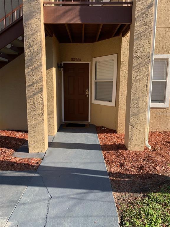 The exterior view shows a brown front door under a balcony with a concrete walkway — 8834 CORAL PALMS COURT UNIT A, KISSIMMEE, FL