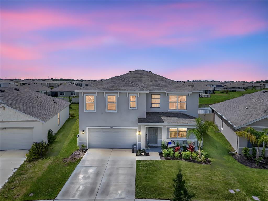 A two-story suburban house with a gray exterior, a two-car garage, and a concrete driveway — 8237 JUNING COVE, WESLEY CHAPEL, FL