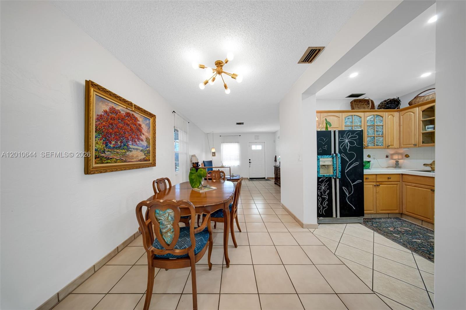A dining area with tile floors leads into a kitchen with wood cabinets and appliances — 7250 SW 34th St Rd, Miami FL 33155, MIAMI, FL