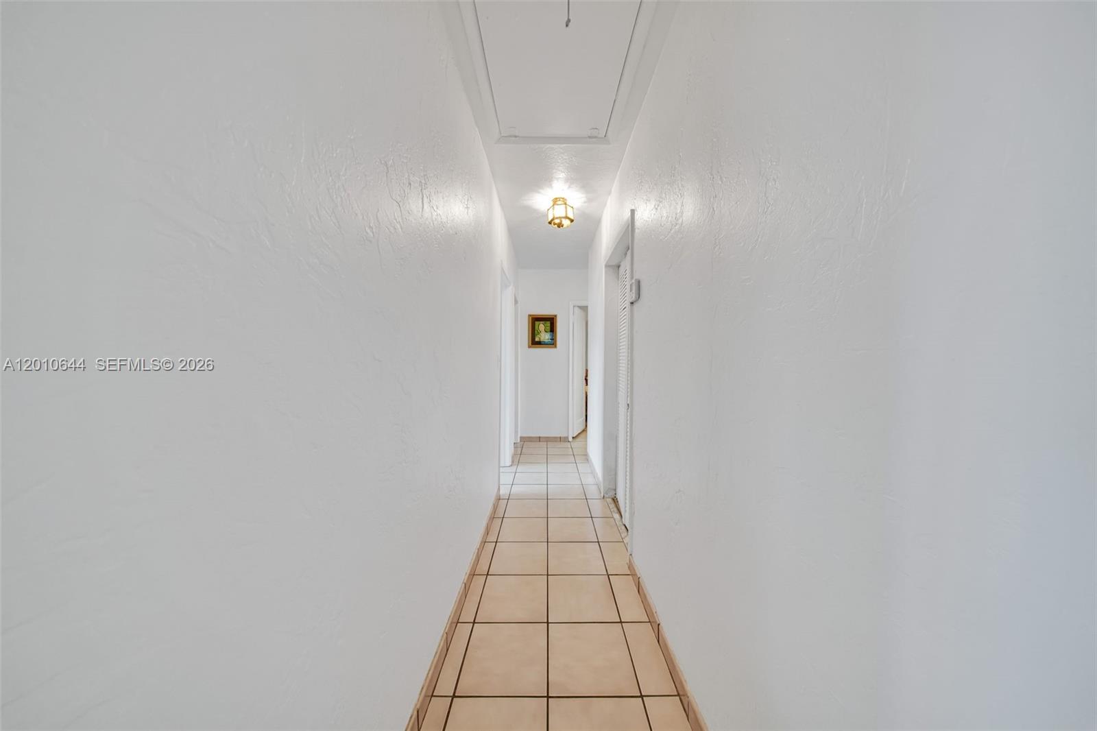 A narrow hallway features white walls, tan tile flooring, and a ceiling-mounted light fixture — 7250 SW 34th St Rd, Miami FL 33155, MIAMI, FL