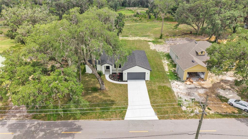 An aerial view shows a modern white house with a dark roof and concrete driveway — 3611 E GASKINS ROAD, BARTOW, FL