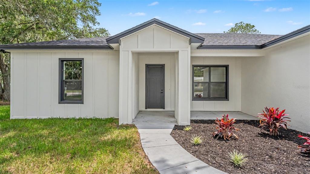 A white house with board-and-batten siding, a dark front door, and a concrete walkway — 3611 E GASKINS ROAD, BARTOW, FL