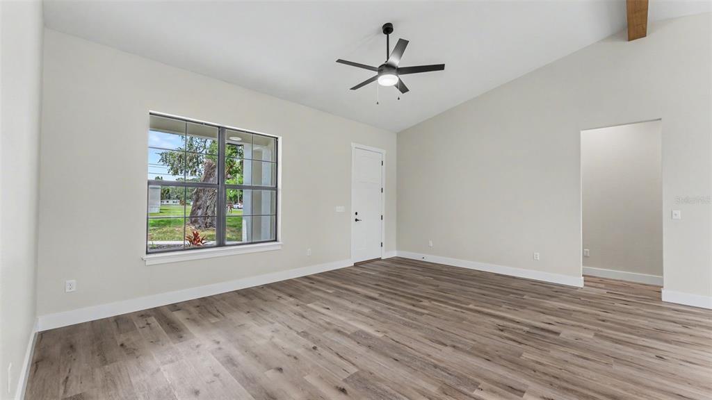 An empty room features light-colored walls, wood-look flooring, a ceiling fan, and a large window — 3611 E GASKINS ROAD, BARTOW, FL