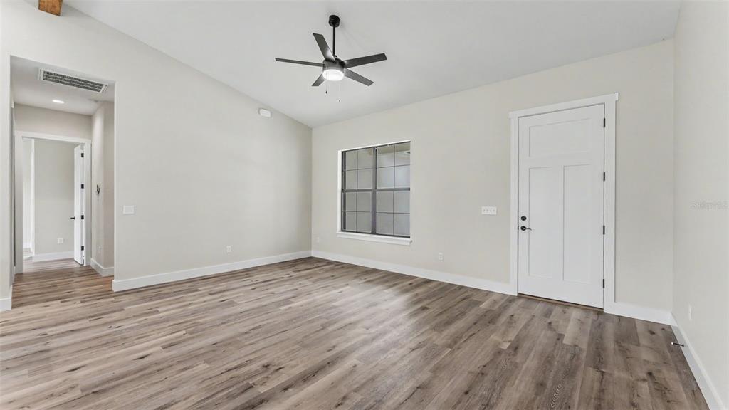 An empty room with light-colored walls, wood-look flooring, a ceiling fan, and a white door — 3611 E GASKINS ROAD, BARTOW, FL
