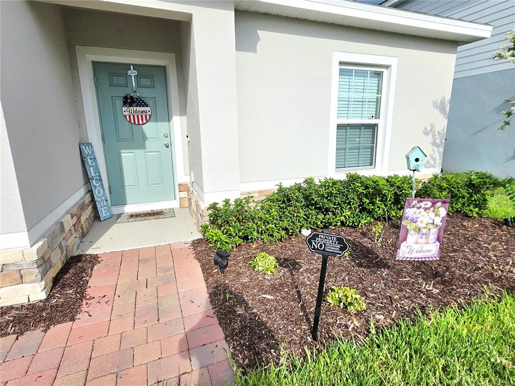 A light blue front door with a brick walkway and landscaping in front of a house — 1121 LEXINGTON LANE, HAINES CITY, FL