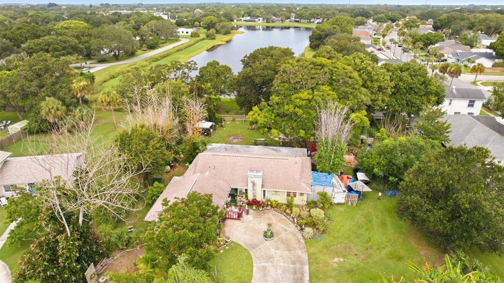 An aerial view shows a single-story house with a circular driveway, trees, and a lake — 517 LINDA LANE, MELBOURNE, FL
