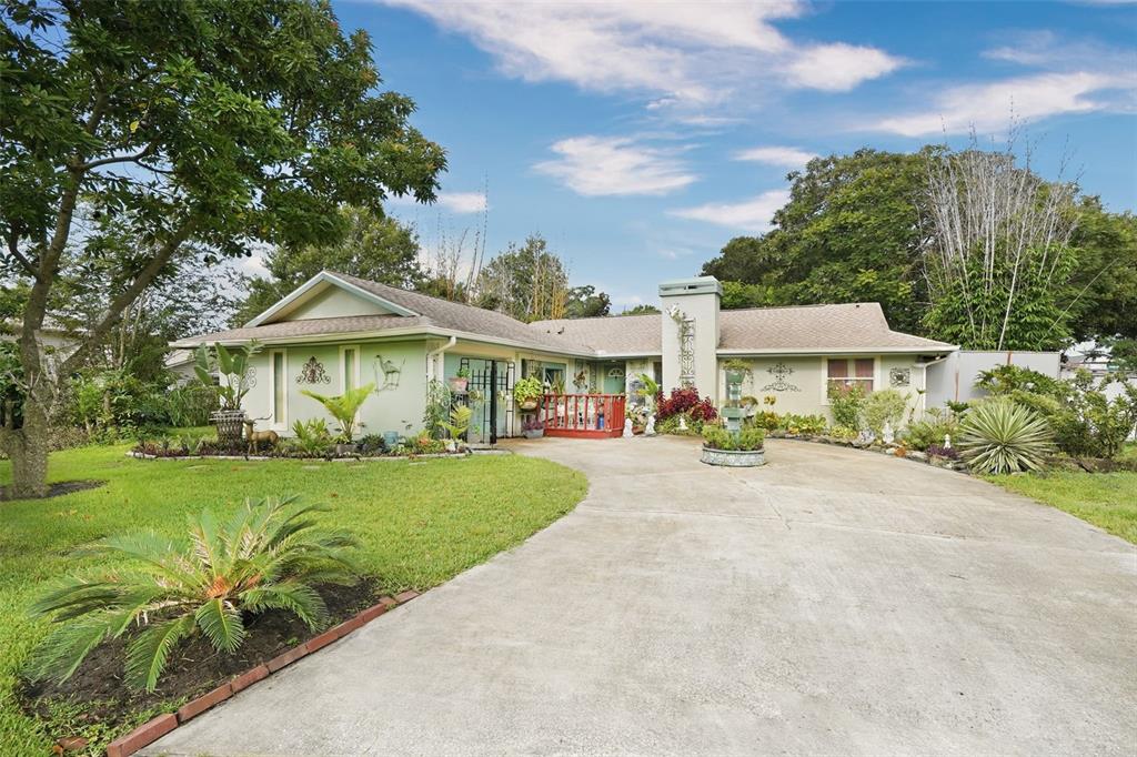 A single-story house with a concrete driveway, a green exterior, and a landscaped front yard — 517 LINDA LANE, MELBOURNE, FL