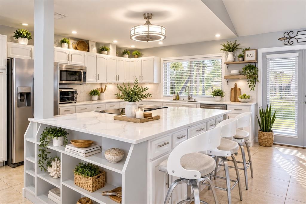 A bright kitchen features white cabinetry, a large marble-topped island, and stainless steel appliances — 517 LINDA LANE, MELBOURNE, FL