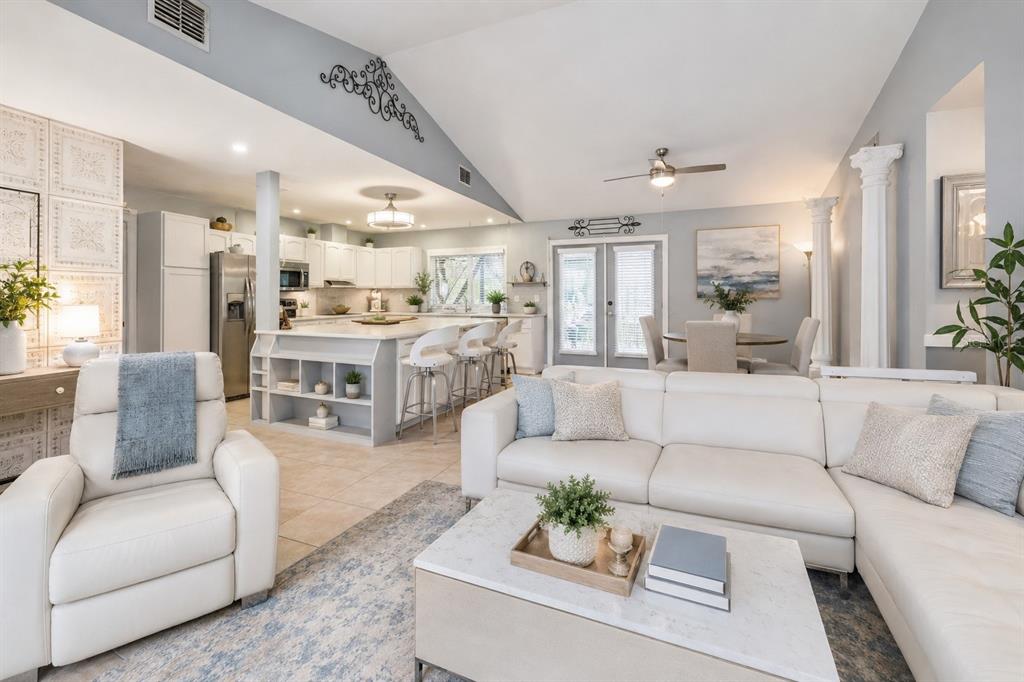 An open-concept living room and kitchen featuring white cabinetry, a large island, and vaulted ceilings — 517 LINDA LANE, MELBOURNE, FL