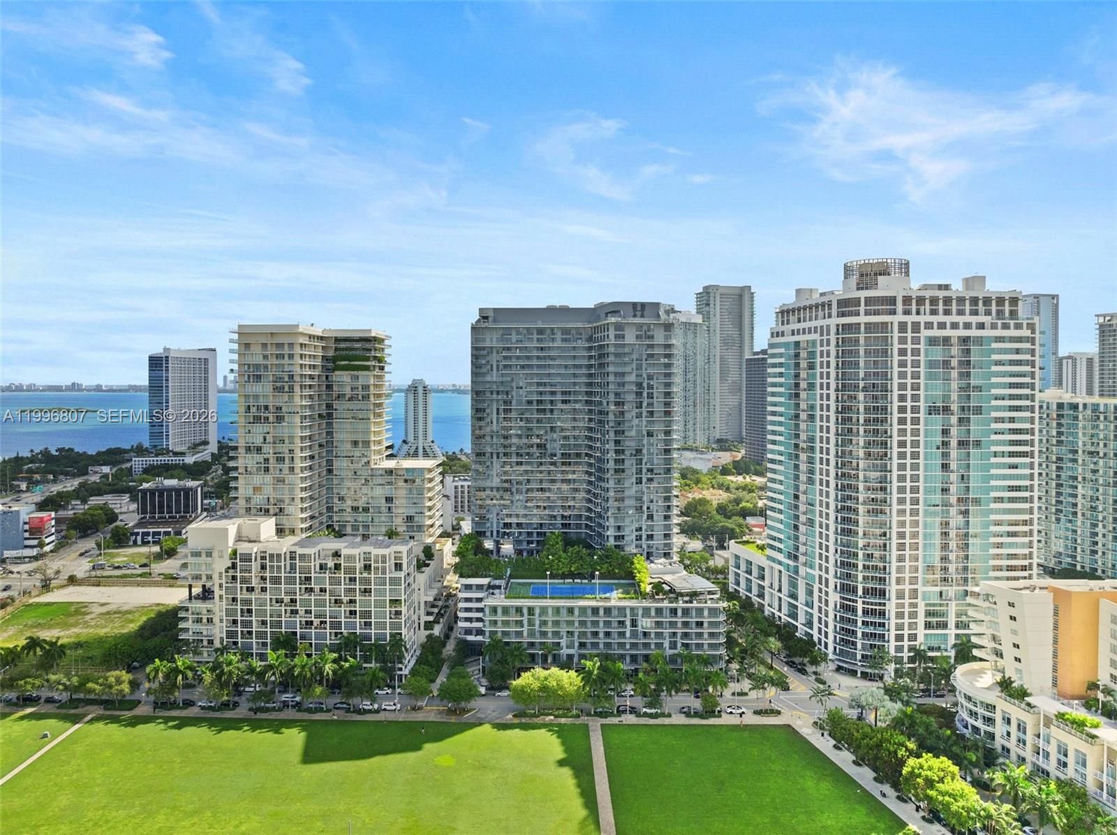 An aerial view shows several high-rise apartment buildings overlooking a park and the ocean — 121 NE 34th St # 2314, Miami FL 33137, MIAMI, FL