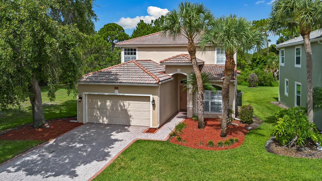 A two-story tan stucco house with a tiled roof, garage, and palm trees in front — 3516 NW Deer Oak Drive, Jensen Beach FL 34957, JENSEN BEACH, FL