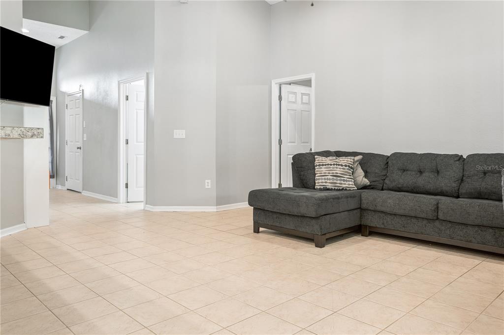 A living room with light tile flooring, gray walls, and a dark gray sectional sofa — 5701 SWEET WILLIAM TERRACE, LAND O LAKES, FL